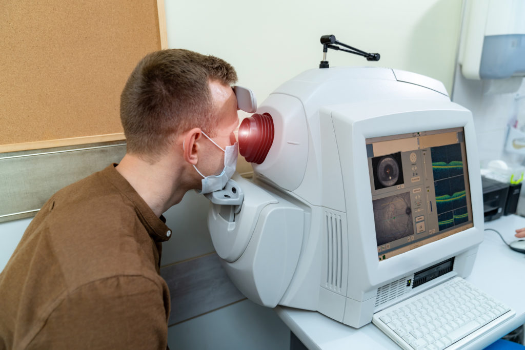 Muž sa díva do prístroja na očné vyšetrenie.