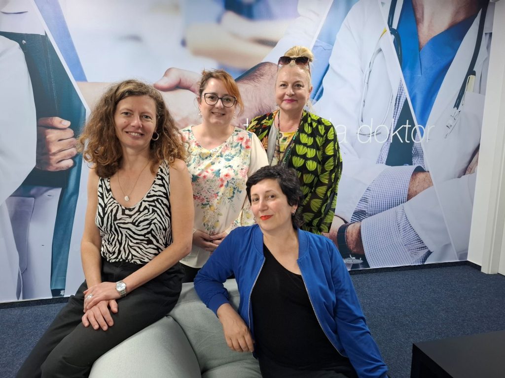 Na spoločnej fotografii v priestoroch TV Doktor. V popredí sú Andrea Bila, Valérie . Bertrand-Vivancos - sedia na sedačke. Pri nich stoja E. Fričovská a M. Holíková. Za nimi je stena, kde je vidno fototapetu, na ktorej sú vyobrazení lekári a text doktor (časť názvu televízia doktor).